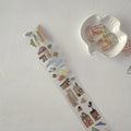 Decorative tape with house pattern next to a white dish with paper clips on a light gray surface
