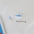 Sticker with a bowl of cereal, toothbrush, and cup on a textured surface with 'morning' text.
