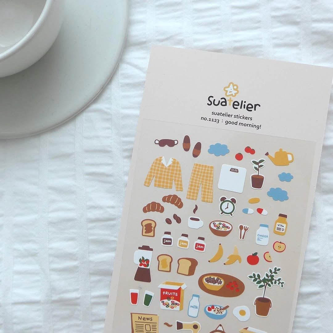 Sheet of stickers with various illustrations on a white surface next to a cup.