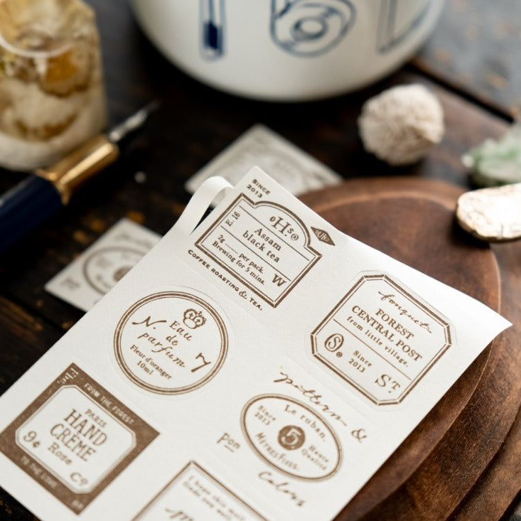 Sheet of printed labels on a wooden surface with stationery items.