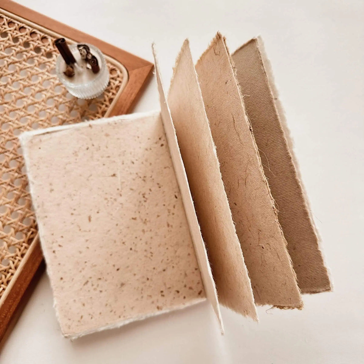 Handmade Paper A6 Notebooks in natural brown tones with a wooden tray behind on white