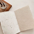 Two pieces of natural fiber paper on a light surface with a wooden coaster in the background.