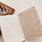 Two square pieces of textured paper on a light surface