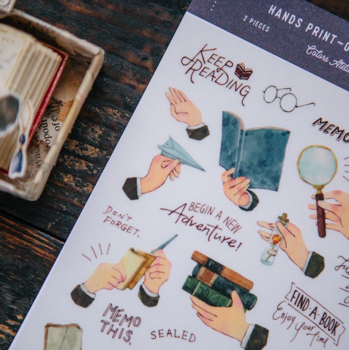 Sheet of illustrated stickers with text and hand-drawn graphics on a wooden surface