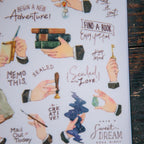 Decorative paper with illustrated hands holding books, letters, and other items with motivational text on a wooden surface.