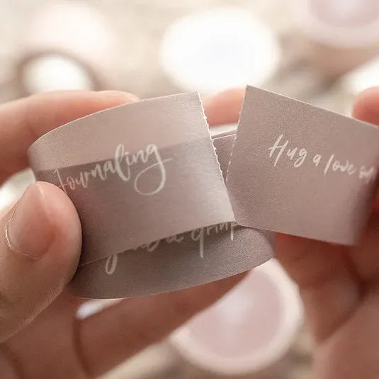 Hands holding two small pieces of paper with text on a blurred background