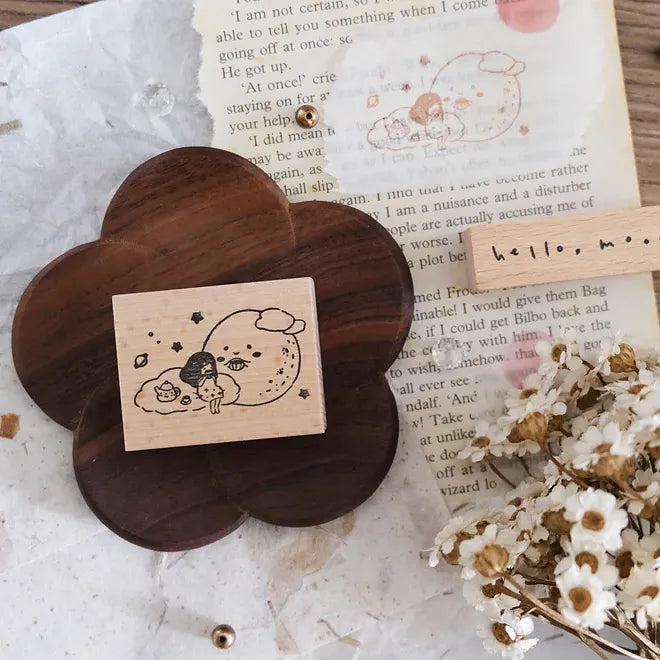 Wooden flower-shaped holder with a rubber stamp on a textured surface with flowers and text.