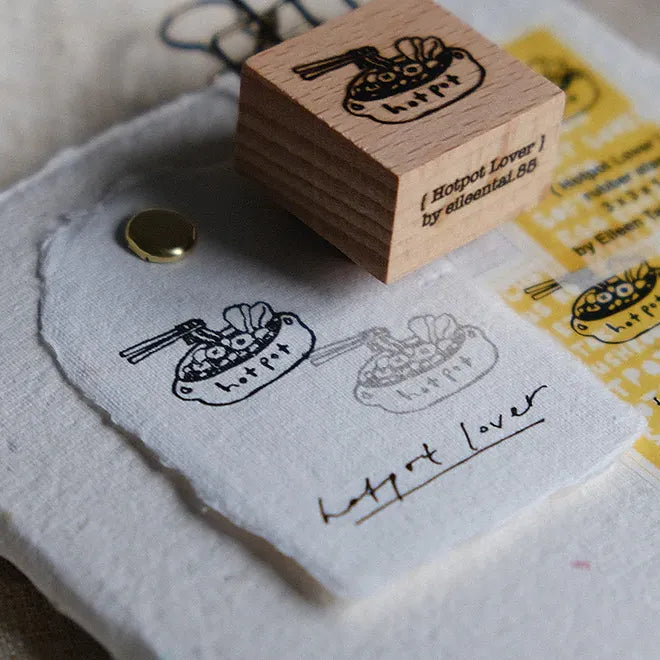 Wooden stamp with 'Hotpot Lover' design on a piece of paper.