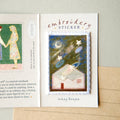An embroidered sticker card featuring a small stitched house with stars and a moon on the front, labeled 'embroidery STICKER' and signed 'shop teddy'.