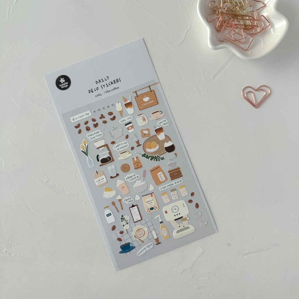 Pack of decorative stickers with illustrations on a white surface with paper clips.