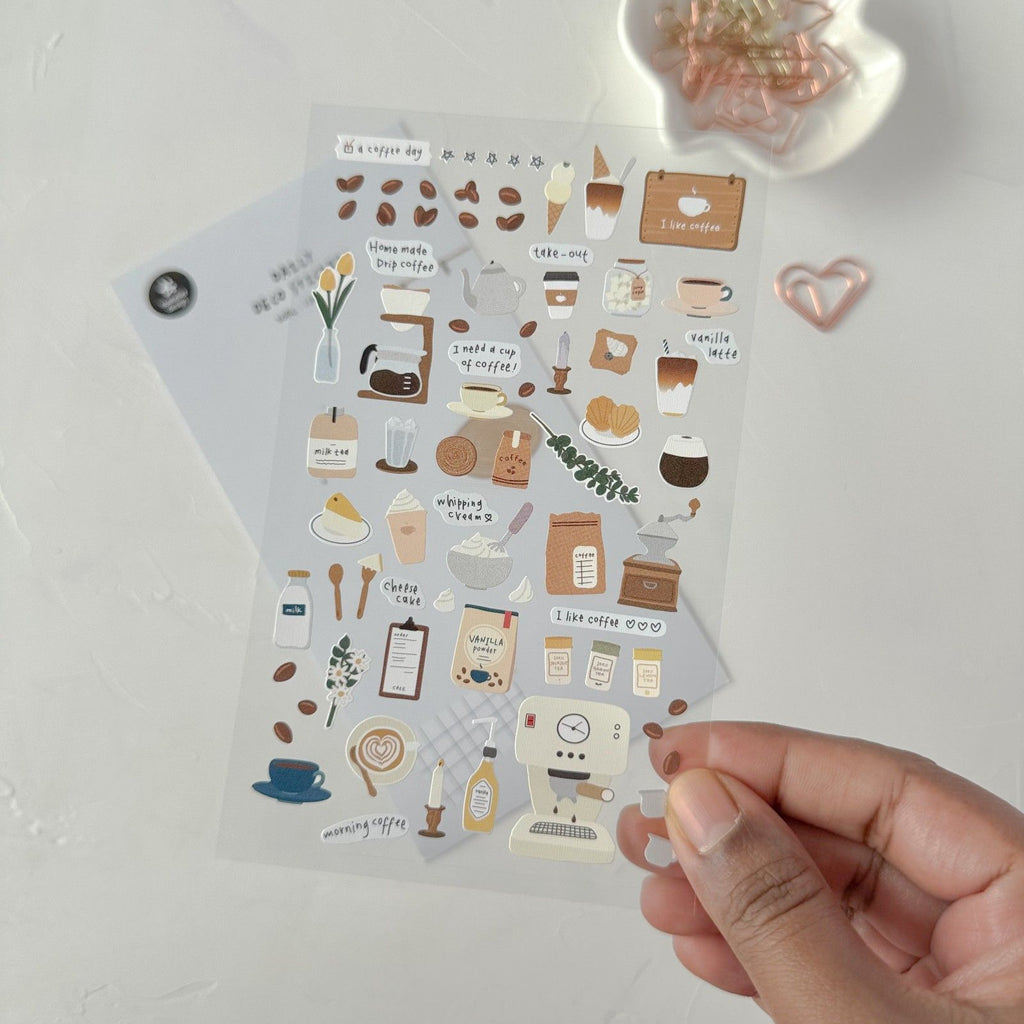 Sheet of decorative stickers with coffee-themed designs held by a hand on a light background.