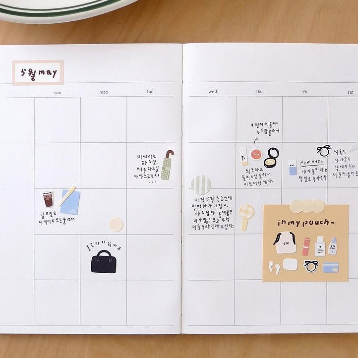 Open planner with a calendar and notes on a wooden surface, from the In My Bag Sticker Sheet