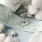 Decorative tape with nature-themed illustrations on a surface with cotton balls.