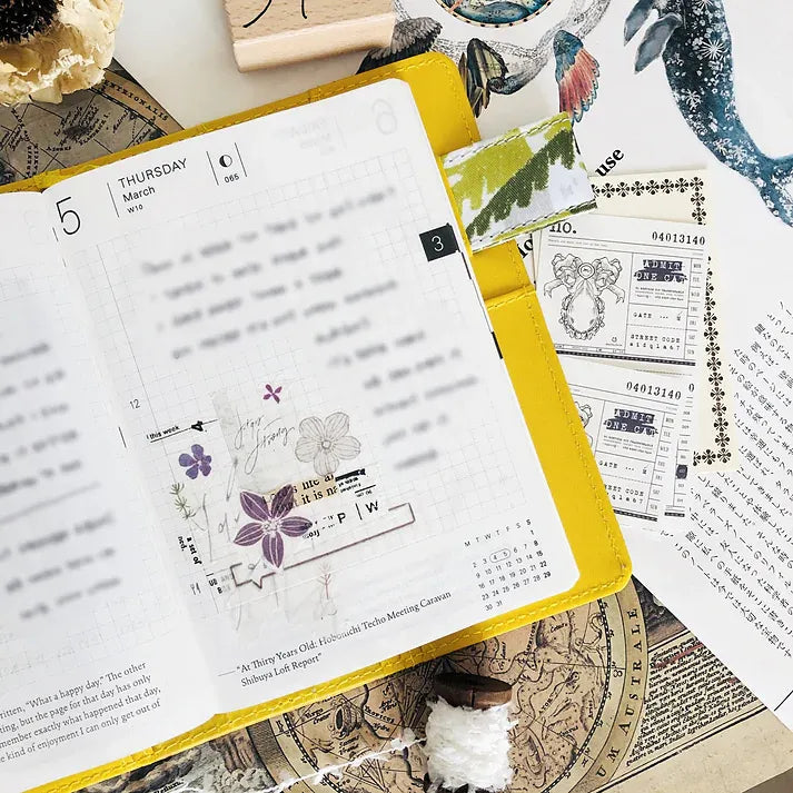 Open planner decorated with vintage-style Addict Washi Tape strips, overhead styled craft view