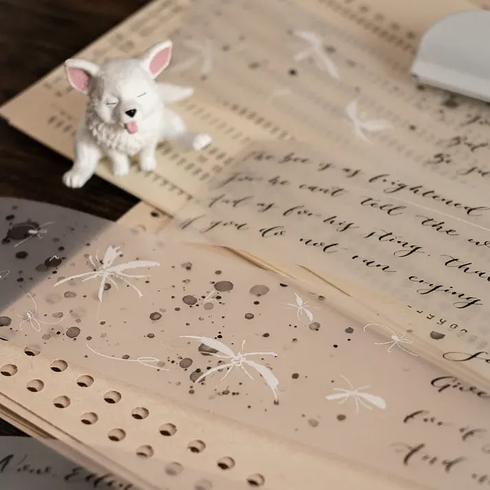 White dog figurine on an open book decorated with Butterfly PET Tape text and butterfly motifs