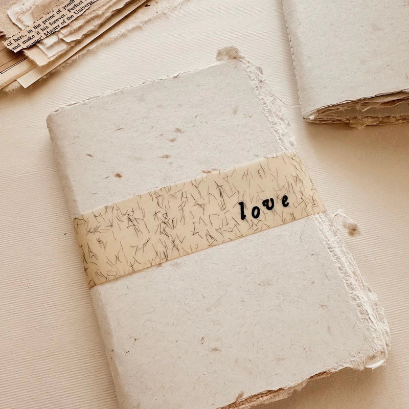 Handmade Paper Passport Size Journal Insert with a love paper band on a textured surface
