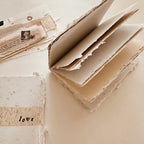 Stack of handmade paper with a piece of newspaper and a small photo in the background.