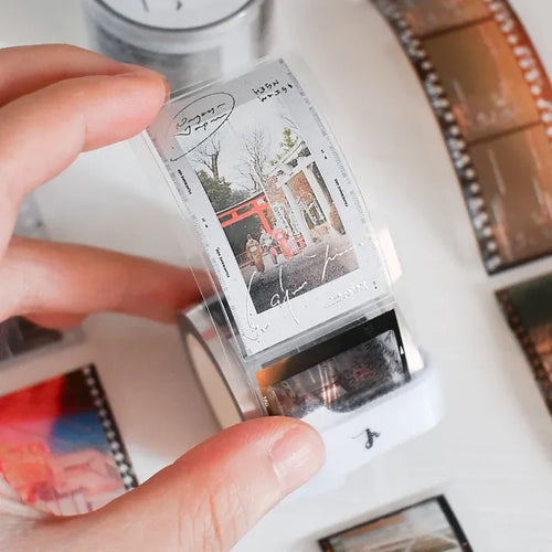Person holding a roll of 35mm film with a close-up of the film strip in the foreground.