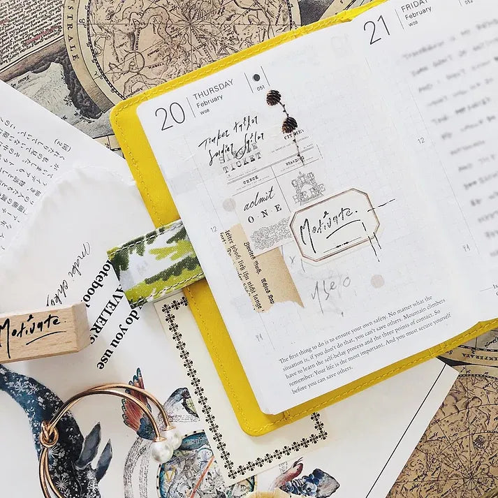 Yellow-bound notebook decorated with Addict Washi Tape vintage elements on a textured surface