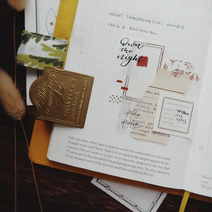 Open book styled with Addict Washi Tape, a gold bookmark and deco pieces on a wooden surface