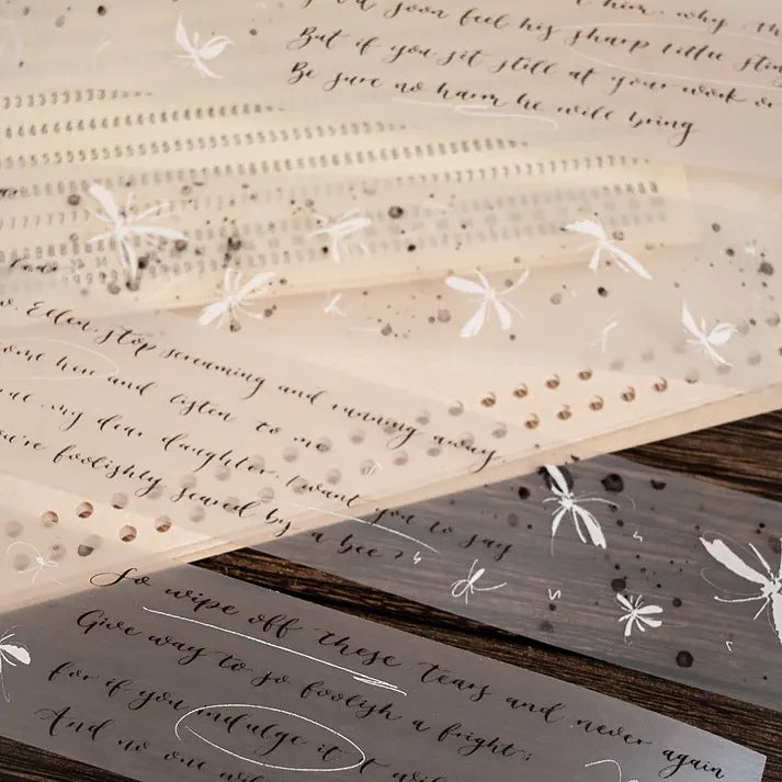 Butterfly PET Tape strips layered with embellishments on decorative paper on a warm wooden surface