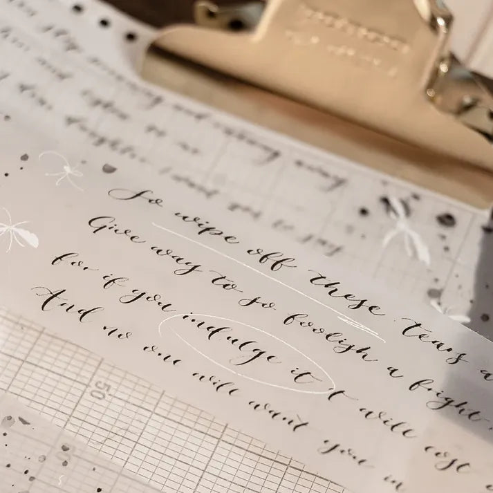 Butterfly PET Tape with white butterflies and handwritten text held by a gold clip on grid paper