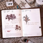 Open planner with floral designs and text on a textured surface