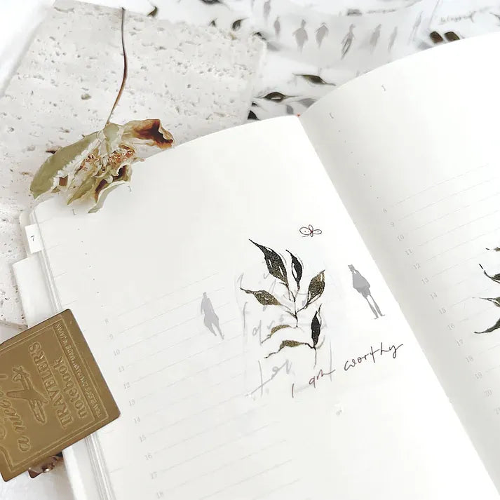Notebook decorated with a green Leaves PET Tape leaf design and a pen on a clean white surface