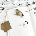 Notebook with a pressed flower on top, surrounded by floral patterns