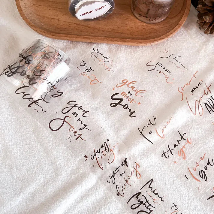Clear strip of Magic Time Rose Gold PET Tape with handwritten-style text laid on a white surface