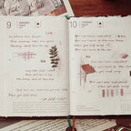 Open notebook with handwritten text and decorative elements on a wooden surface