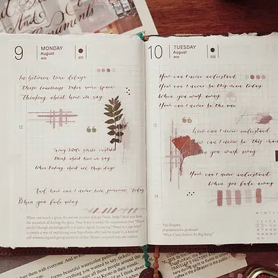 Open notebook with handwritten text and decorative elements on a wooden surface