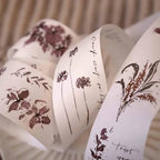 White ribbons with floral designs and text on a neutral background