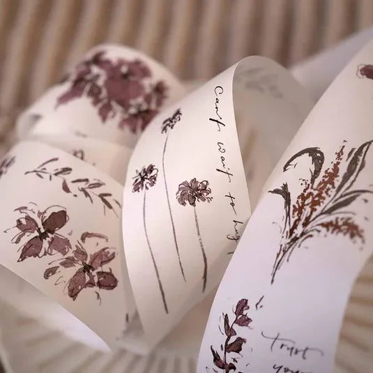 White ribbons with floral designs and text on a neutral background