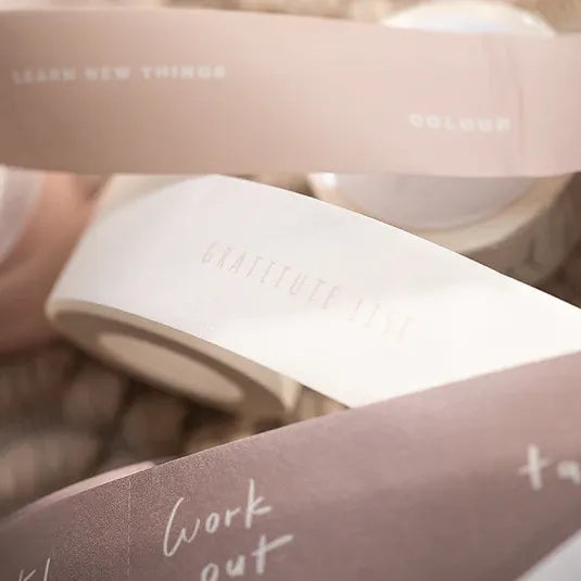 Close-up of pink and white Healer Washi Tape rolls with printed text on a blurred background