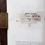 Notebook page with text 'your smile can light up my room' and a gold pen on top.