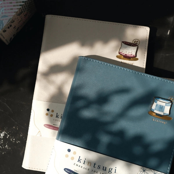 Two notebooks with kintsugi design on a dark surface