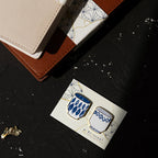 Decorative pins with a blue and white design on a card, placed on a dark surface.
