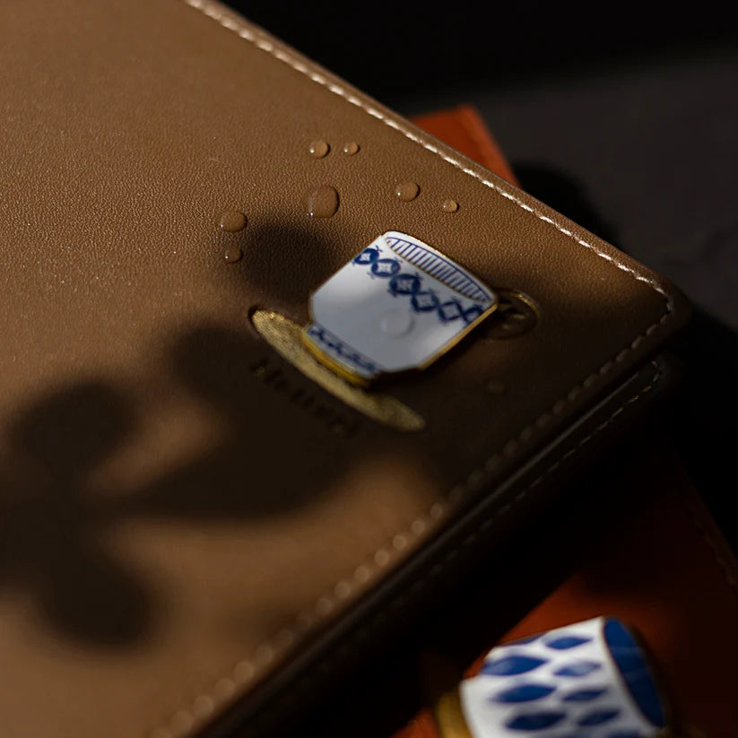 Close-up of a brown leather wallet with a card and dice on a dark background