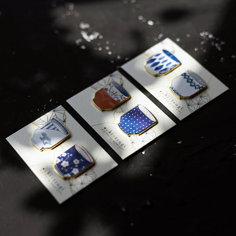 Set of decorative pins on a dark surface with water reflections