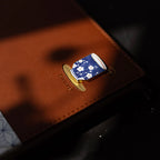 Pin with blue floral design on a brown leather surface