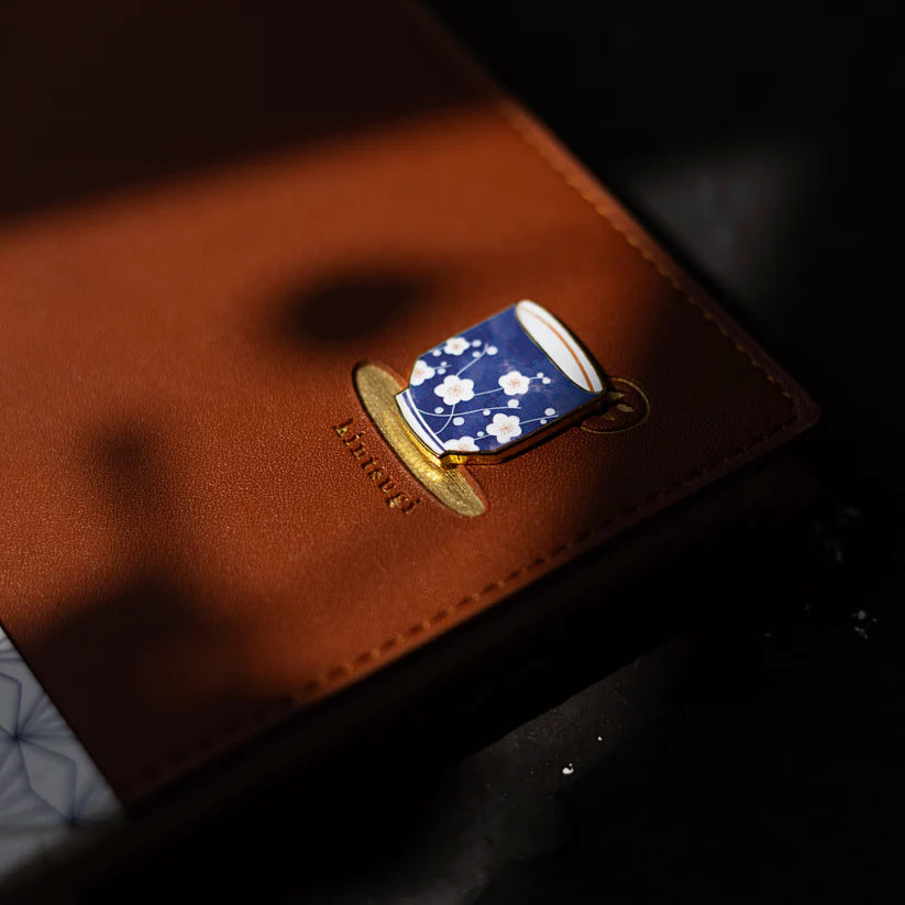 Pin with blue floral design on a brown leather surface