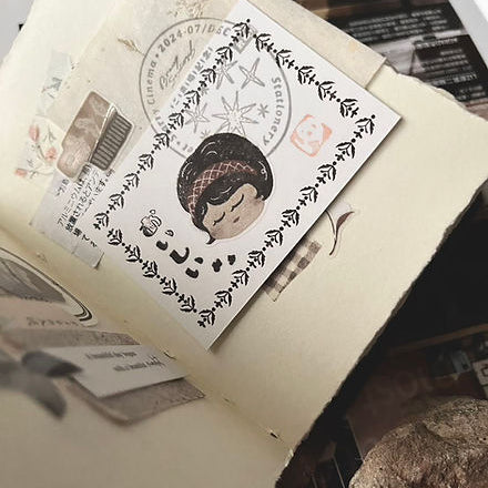 Card decorated with a Kissaten Cafe PET Tape design resting on an open book, styled close-up