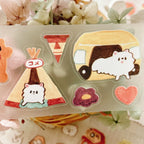 Close-up of pastel sticker strip with rain cloud, umbrella, girl in yellow raincoat, tree, and small dog illustrations.