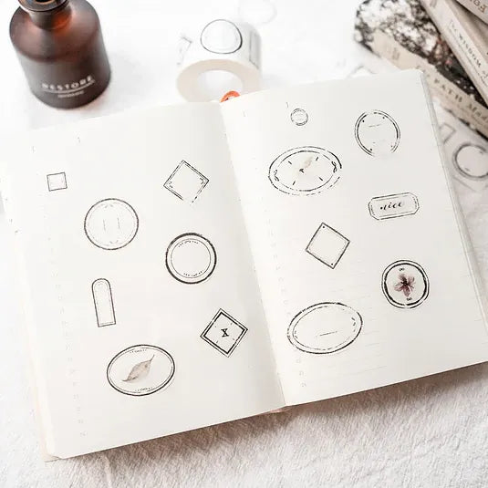 Open notebook decorated with intricate Label Washi Tape designs on a white surface, overhead view