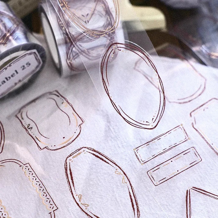 Rose gold foil label shapes from the Label 25 PET Tape on a white surface with a soft-focus backdrop