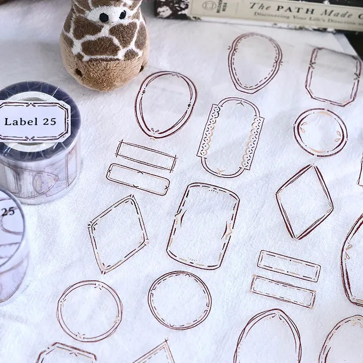Clear geometric Label 25 Rose Gold PET Tape labels styled with a giraffe toy and book behind them