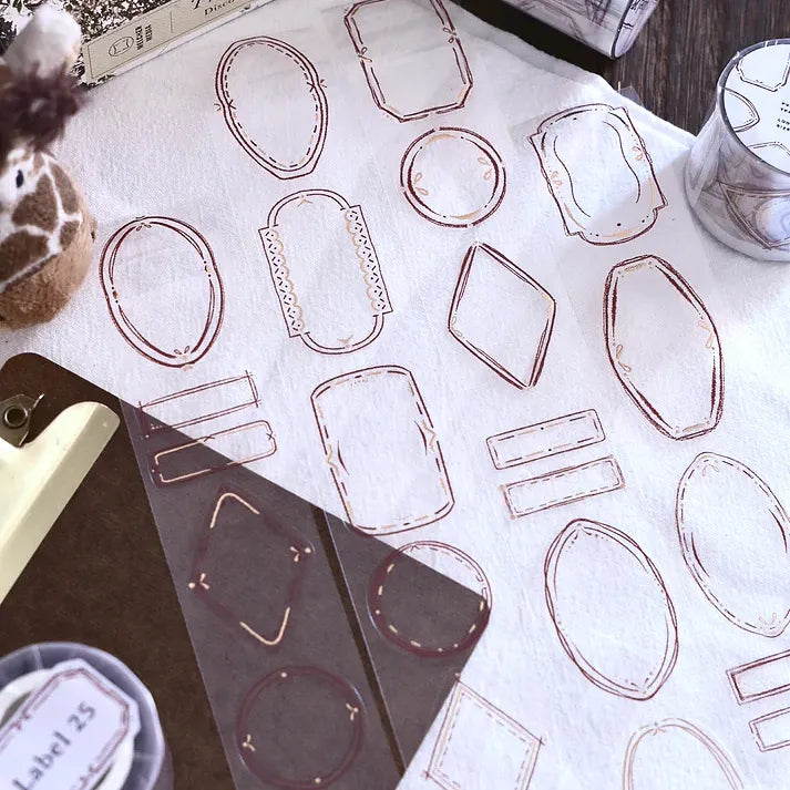 Geometric die-cut labels from the Label 25 Rose Gold PET Tape with a pen and container on white