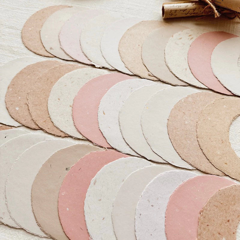 Stack of round, textured paper circles in pastel colors on a light wooden surface.
