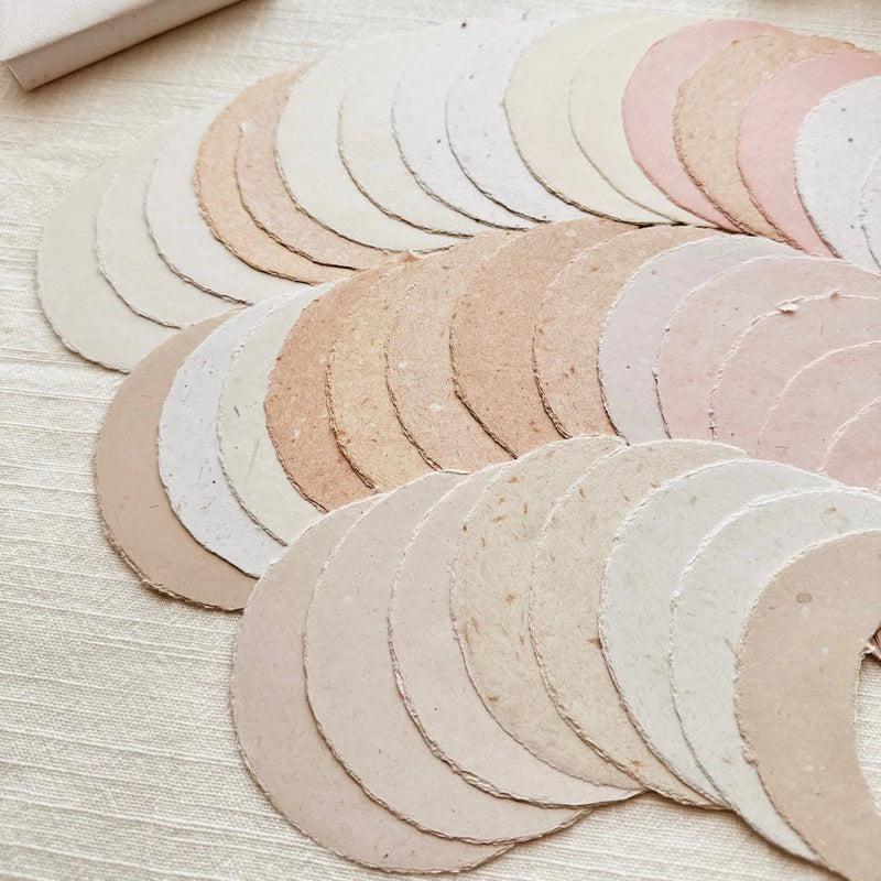 Set of round, beige-colored coasters on a light wooden surface